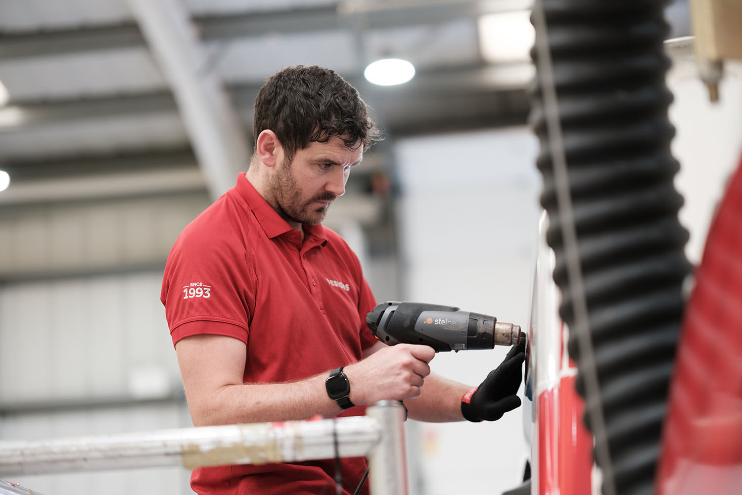 Designs employee using a heat gun to apply vehicle graphic.