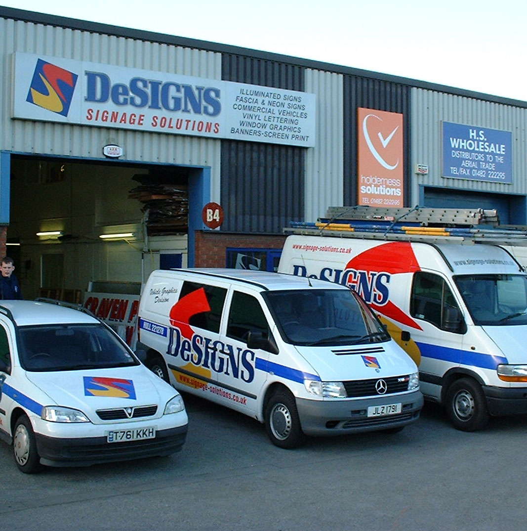 Photo of Designs company building with three cars outside.