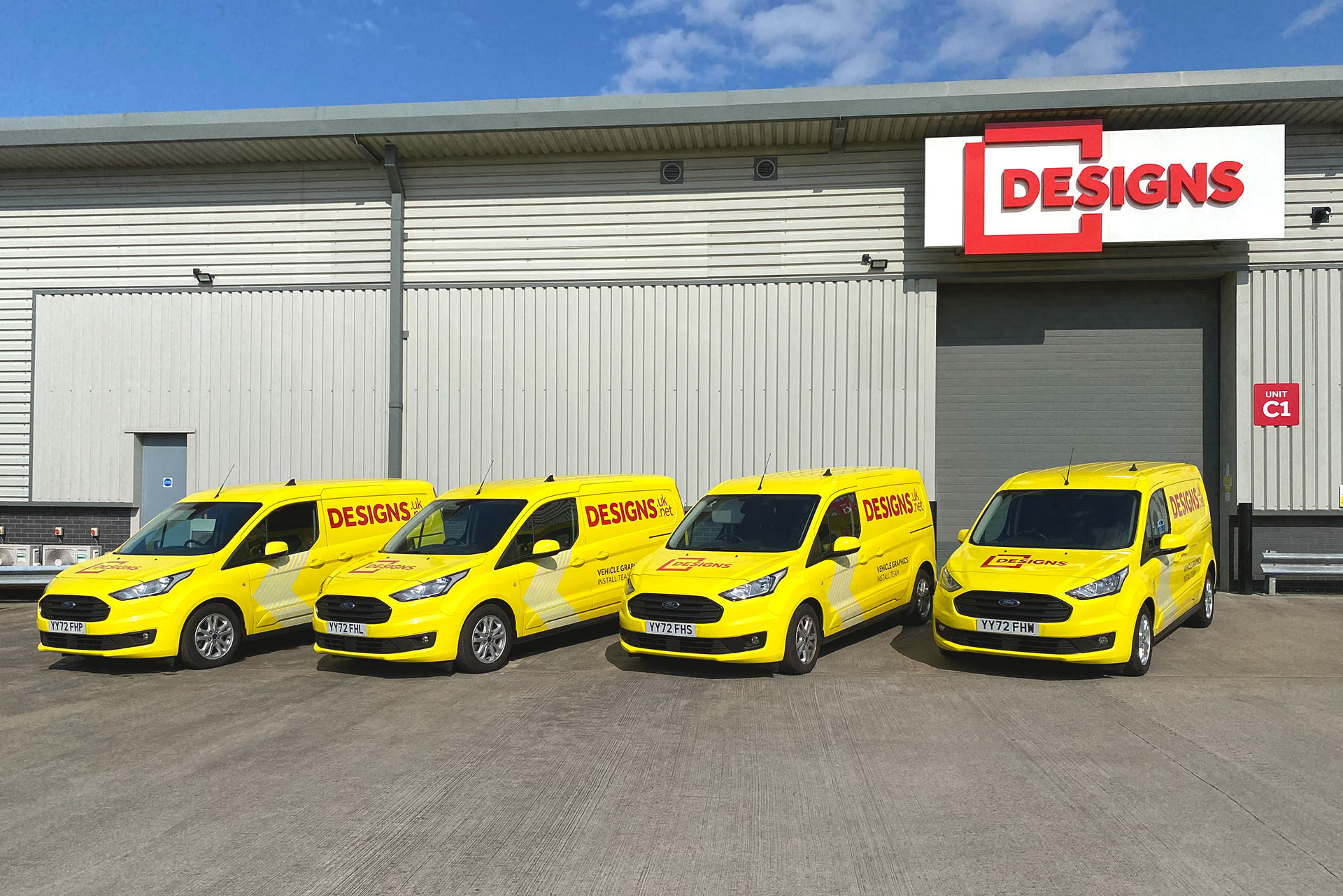 Yellow Ford Designs branded vans outside of the Designs office.