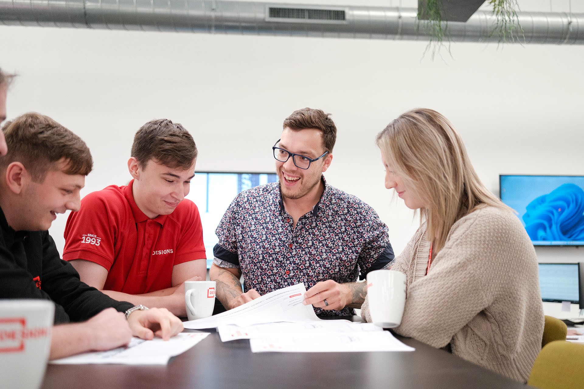 Group of Designs employees sat at a table discussing.