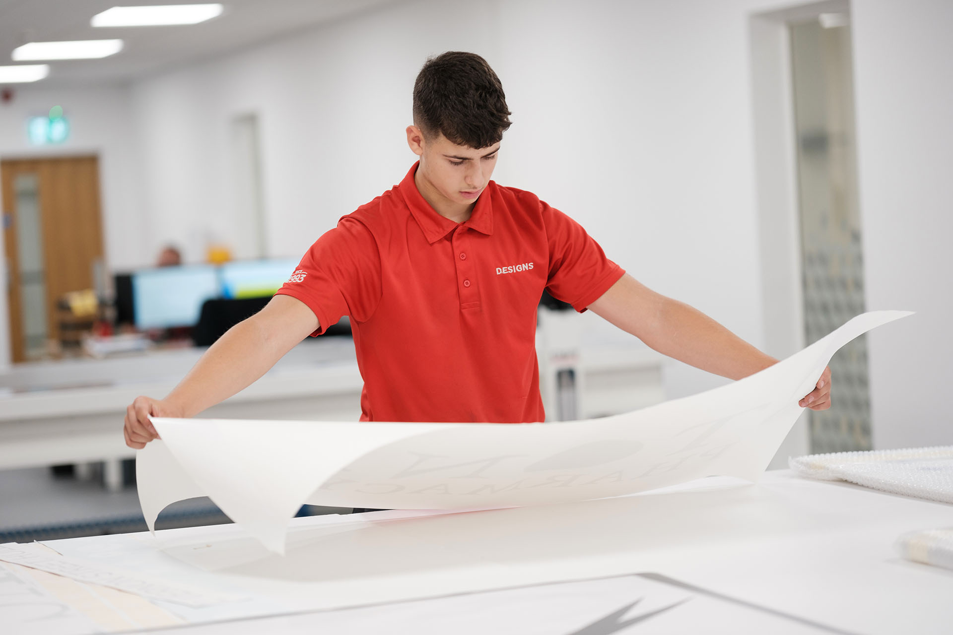 Designs employee looking at a large piece of paper.